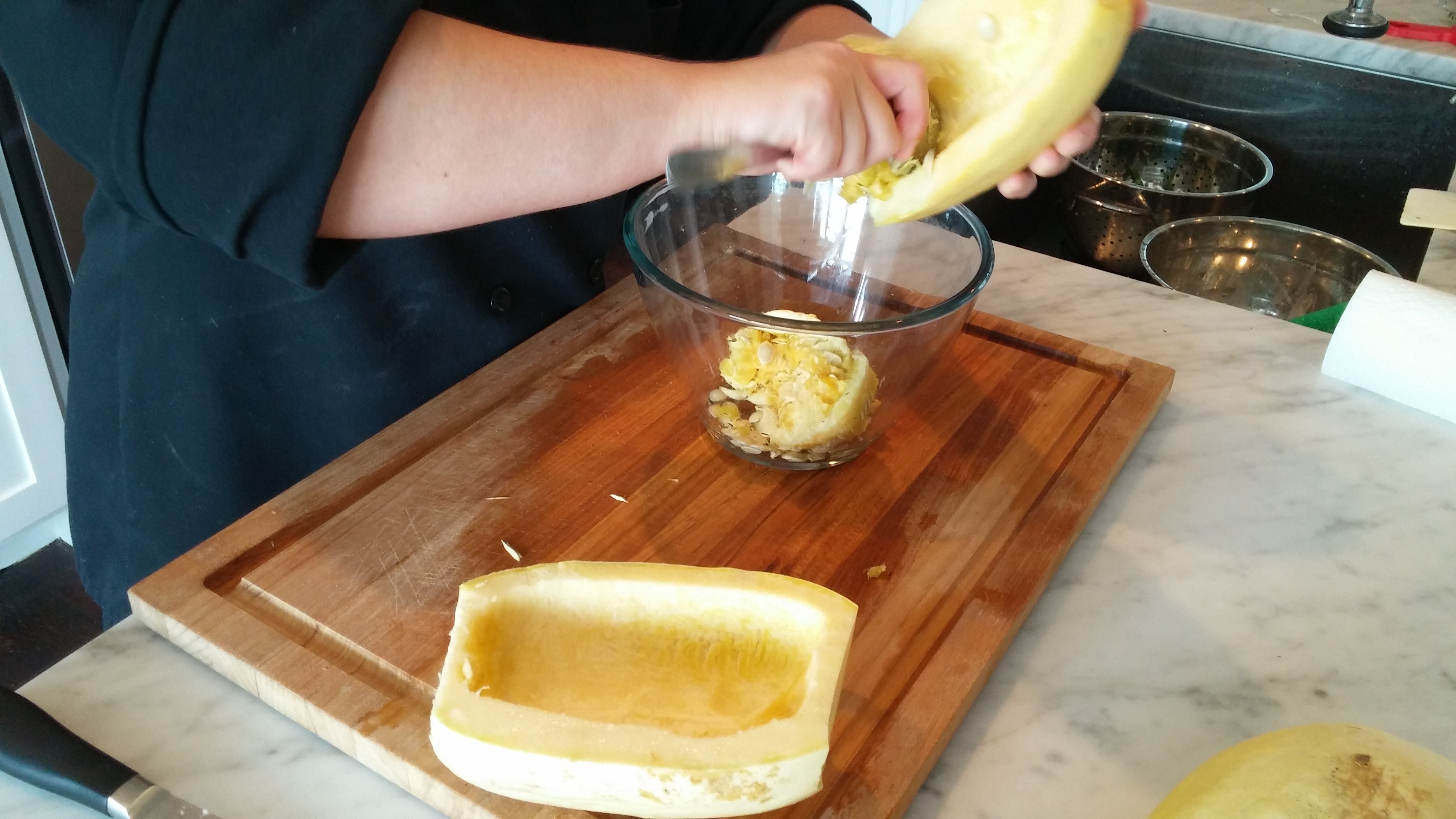 Remove the seeds from a spaghetti squash with a kitchen spoon. 